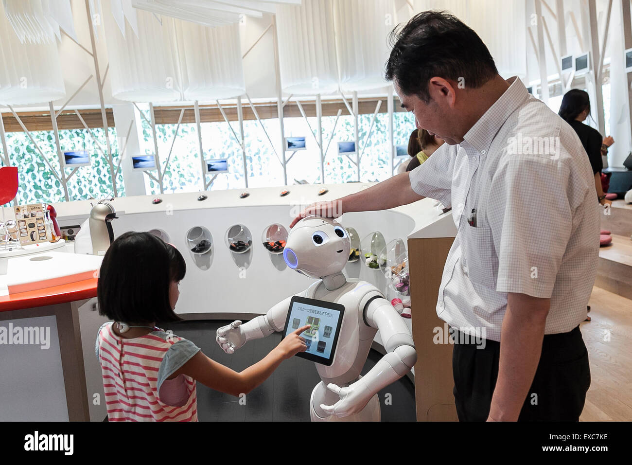 Tokyo, Giappone. 11 Luglio, 2015. I clienti a salutare il robot umanoide Pepe sul suo primo giorno come un nuovo membro del personale del Nescafe coffee-shop in Harajuku sulla luglio 11, 2015, Tokyo, Giappone. Sei i robot sono programmati per interagire con le persone mentre introducendo il Nescafe prodotti durante un evento speciale ''Il mondo? Futuro cafe da NESCAFE con pepe'" sabato 11 luglio. Il negozio continuerà a impiegare due robot come regular staff per introdurre il negozio di prodotti e servizi. Credito: Rodrigo Reyes Marin/AFLO/Alamy Live News Foto Stock