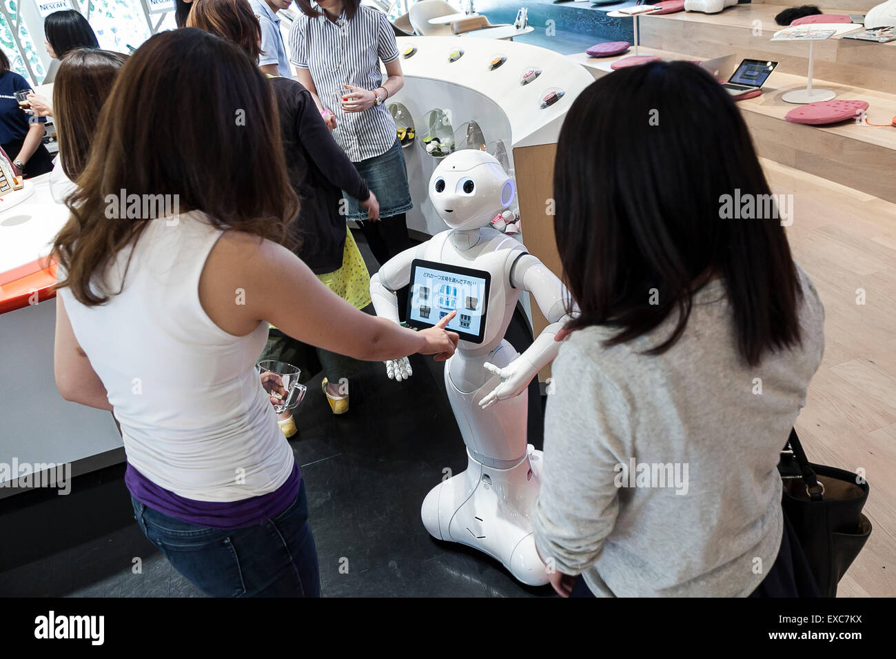 Tokyo, Giappone. 11 Luglio, 2015. I clienti a salutare il robot umanoide Pepe sul suo primo giorno come un nuovo membro del personale del Nescafe coffee-shop in Harajuku sulla luglio 11, 2015, Tokyo, Giappone. Sei i robot sono programmati per interagire con le persone mentre introducendo il Nescafe prodotti durante un evento speciale ''Il mondo? Futuro cafe da NESCAFE con pepe'" sabato 11 luglio. Il negozio continuerà a impiegare due robot come regular staff per introdurre il negozio di prodotti e servizi. Credito: Rodrigo Reyes Marin/AFLO/Alamy Live News Foto Stock