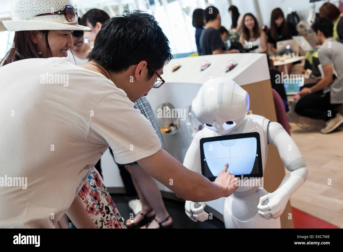 Tokyo, Giappone. 11 Luglio, 2015. I clienti a salutare il robot umanoide Pepe sul suo primo giorno come un nuovo membro del personale del Nescafe coffee-shop in Harajuku sulla luglio 11, 2015, Tokyo, Giappone. Sei i robot sono programmati per interagire con le persone mentre introducendo il Nescafe prodotti durante un evento speciale ''Il mondo? Futuro cafe da NESCAFE con pepe'" sabato 11 luglio. Il negozio continuerà a impiegare due robot come regular staff per introdurre il negozio di prodotti e servizi. Credito: Rodrigo Reyes Marin/AFLO/Alamy Live News Foto Stock