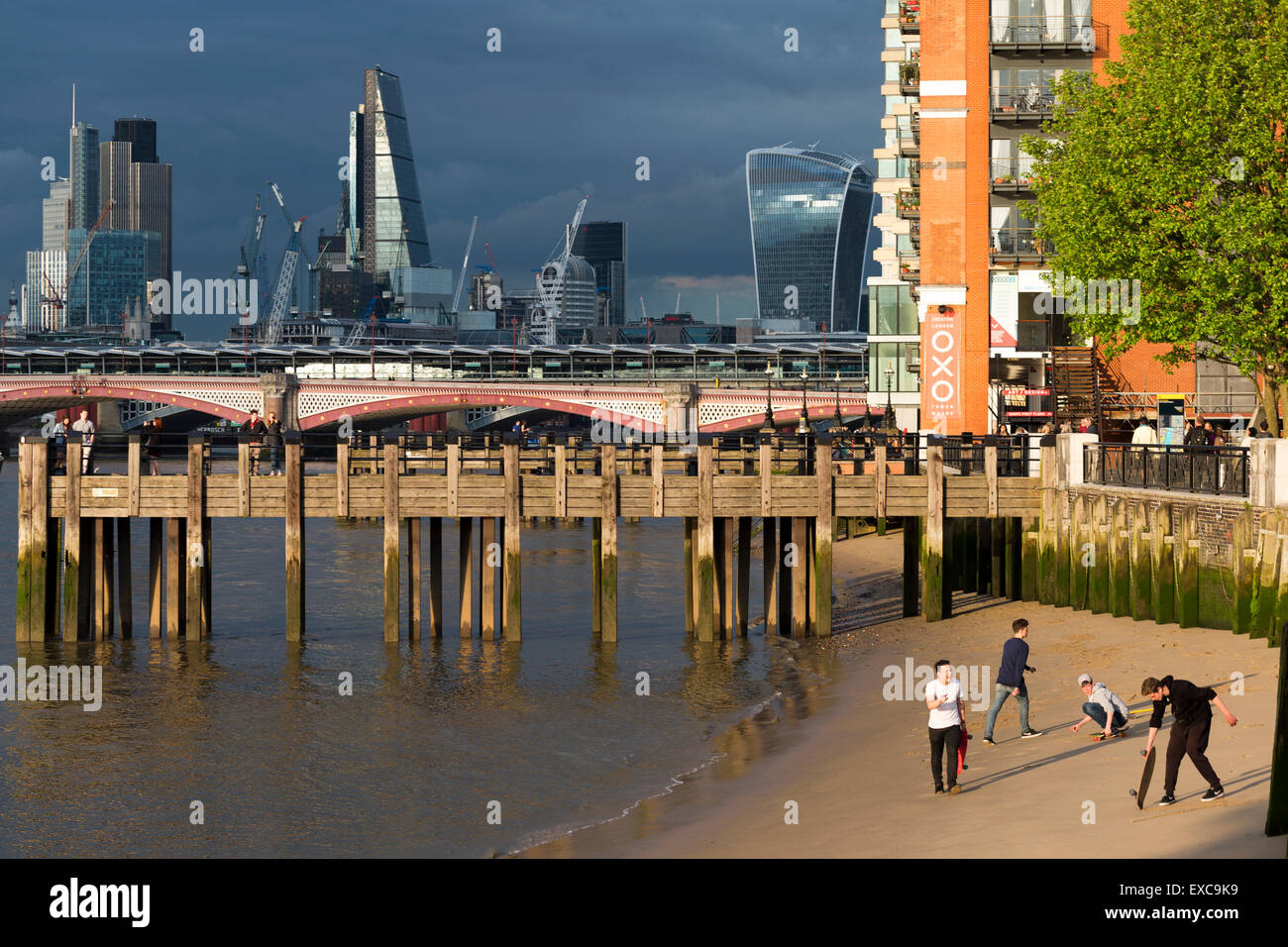 Le persone che giocano su un fiume Tamigi spiaggia vicino la Oxo Tower & Gabriel's Wharf, Southbank Londra, Inghilterra, Regno Unito. Foto Stock