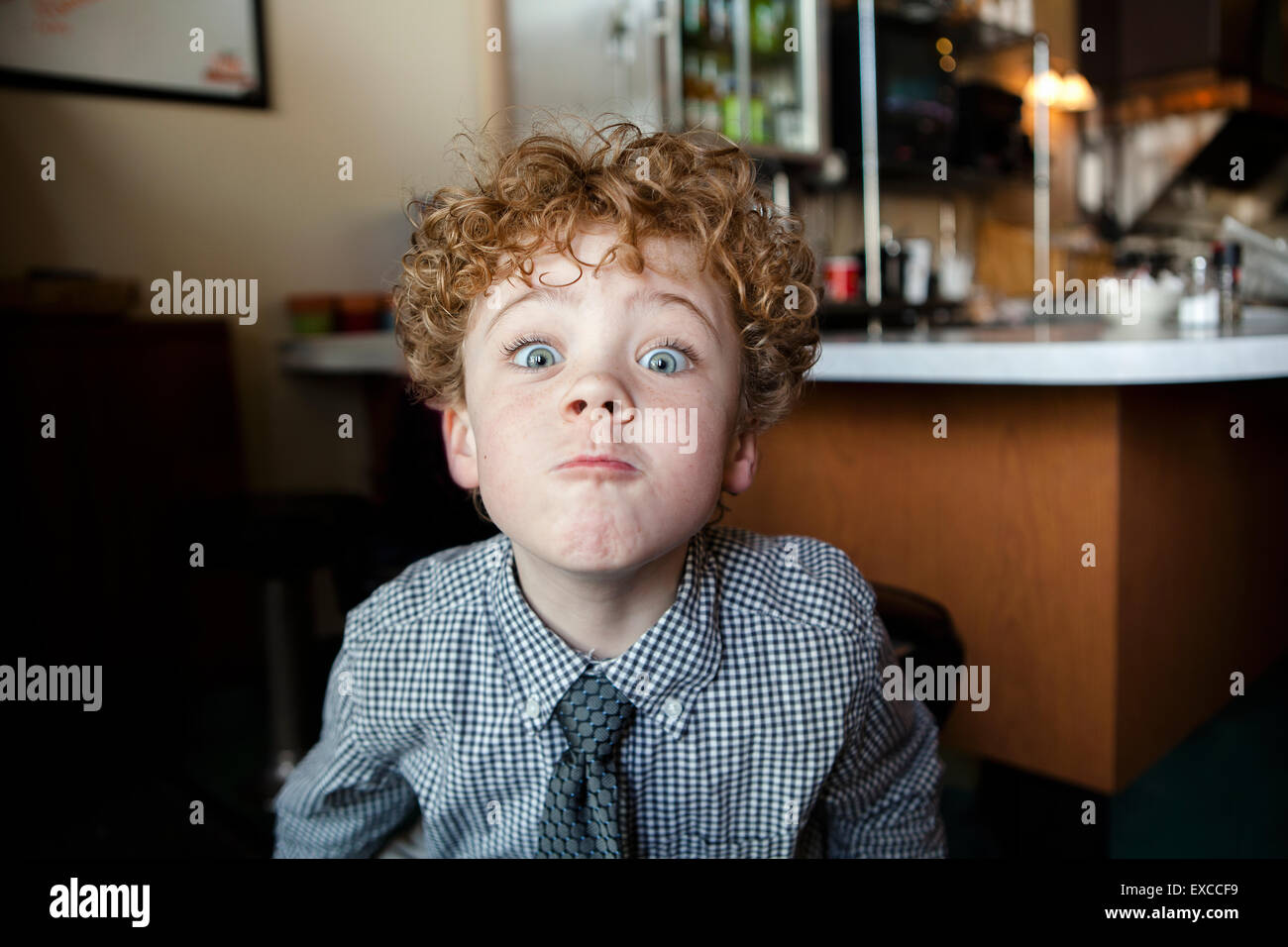 Un 6 anno vecchio ragazzo che indossa un abito camicia e cravatta facendo una faccia di pippo Foto Stock