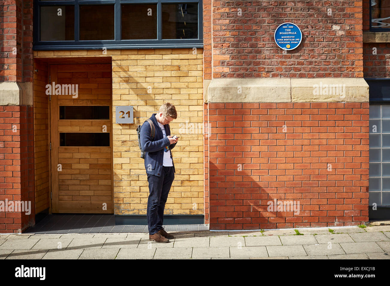 Il vecchio Boardwalk nightclub di Manchester Regno Unito un uomo passa si ferma al testo dal telefono mobile cellulare che stanno guardando sullo schermo texting sm Foto Stock