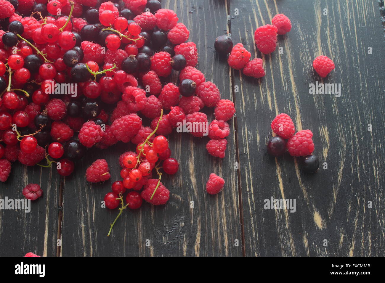 Giacciono su una tavola di legno rosso, nero Ribes, lamponi Foto Stock