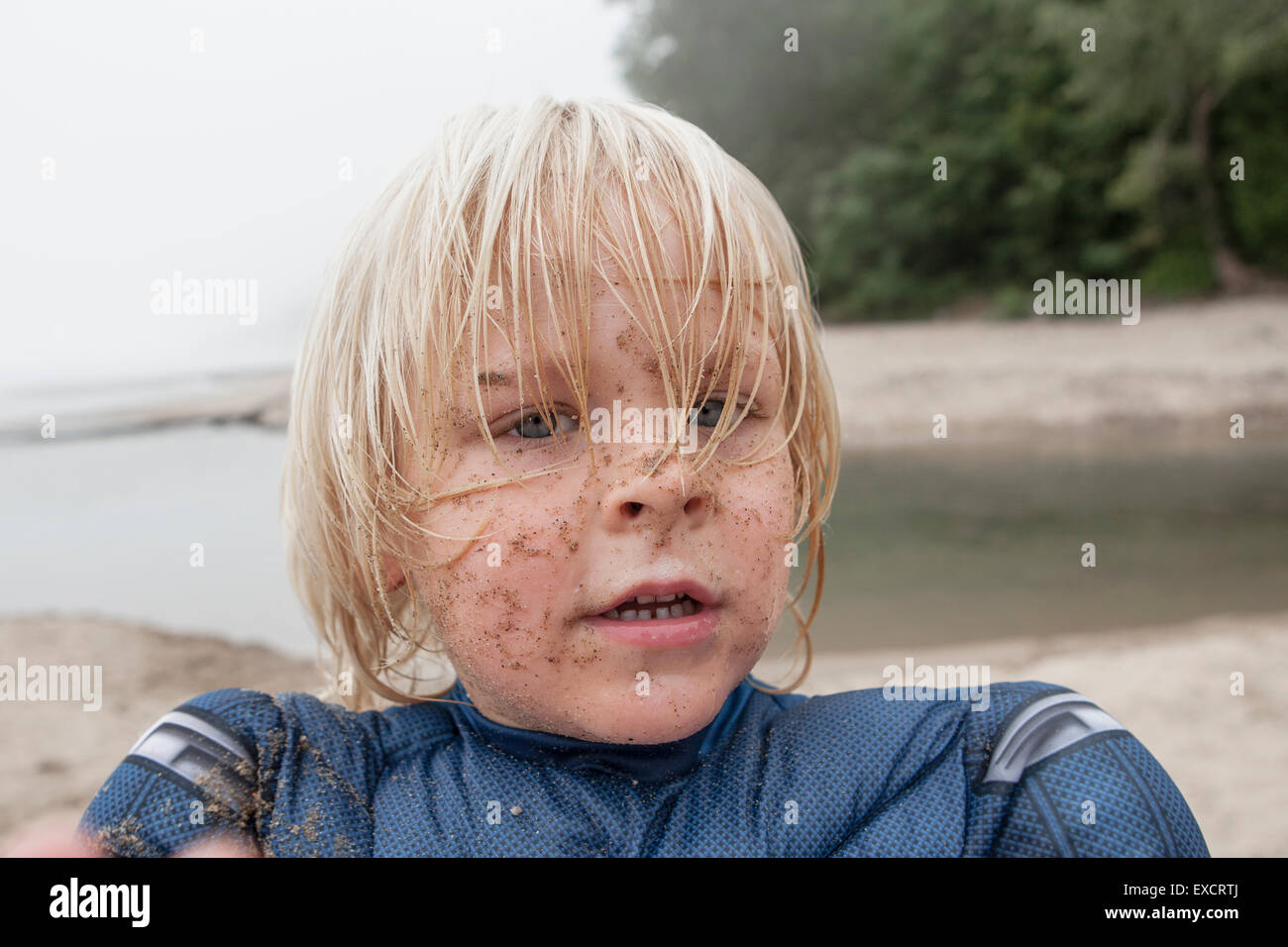 A quattro anni di vecchio ragazzo che indossa un capitano America svolge in costume su una spiaggia di sabbia sul Lago Michigan. Foto Stock
