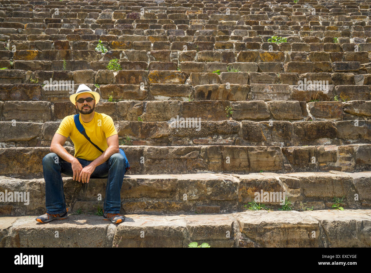 Uomo ispanico in hat seduta al fondo della antica ripidi scalini in pietra di Monte Alban Messico Foto Stock