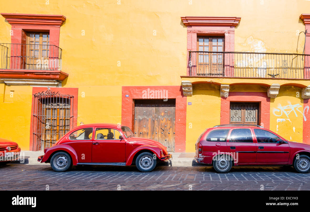 Rosso brillante auto matching rosso brillante e edificio giallo con disallineato di porte e finestre in centro storico di Oaxaca Messico Foto Stock