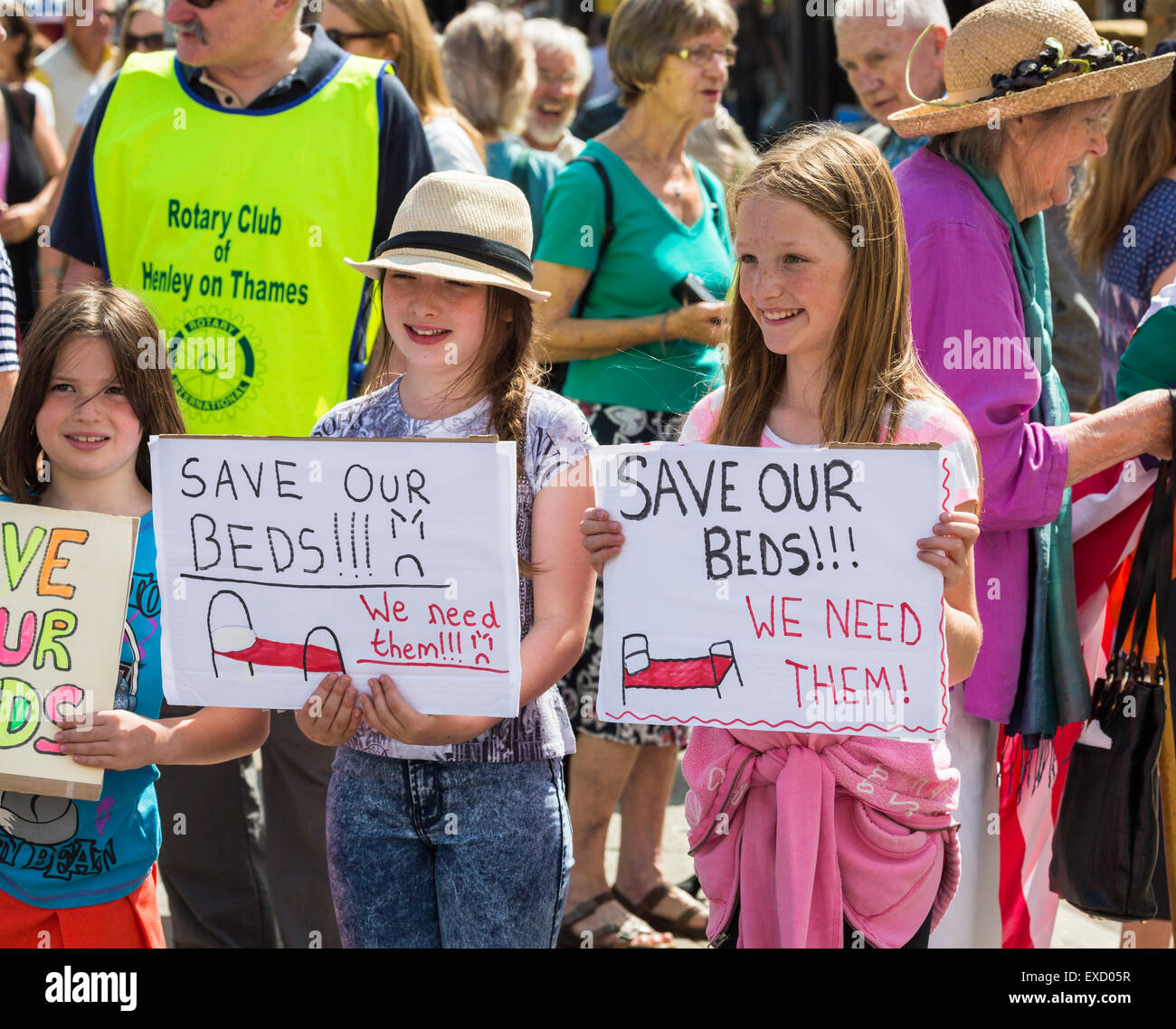 Henley-on-Thames, Regno Unito. 11 Luglio, 2015. Le giovani ragazze in una folla di dimostranti tenere fatti in casa a base di cartelli in un pacifico corteo di protesta per il 'Salva i nostri letti' campagna a Henley-on-Thames, Oxfordshire, Inghilterra, sabato 11 luglio 2015, protestando contro la clinica Oxfordshire messa in esercizio del gruppo i piani per il nuovo campus della salute, Townlands ospedale. Il nuovo ospedale era stato originariamente programmato per avere 18 letti, ora cambiata a 5 letti in una casa di cura per essere costruito accanto all'ospedale, che lascerebbe Townlands senza letti per 6 mesi. Credito: Graham Prentice/Alamy Live News Foto Stock