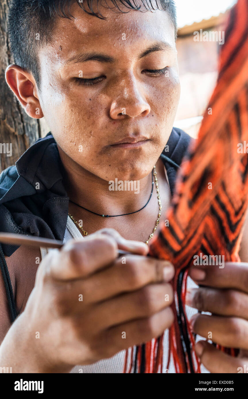 Indigeni Wayuu boy in La Guajira, Colombia la tessitura di un telaio o una cinghia. La tessitura è prevalentemente una femmina di professione in Wayuu communiti Foto Stock