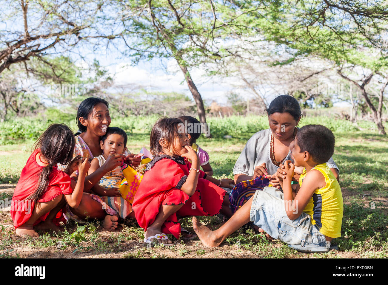 Giovani Wayuu donna e bambini seduti fuori mentre lo tesse in un 'rancheria', o tradizionale insediamento Wayuu in La Guaji Foto Stock