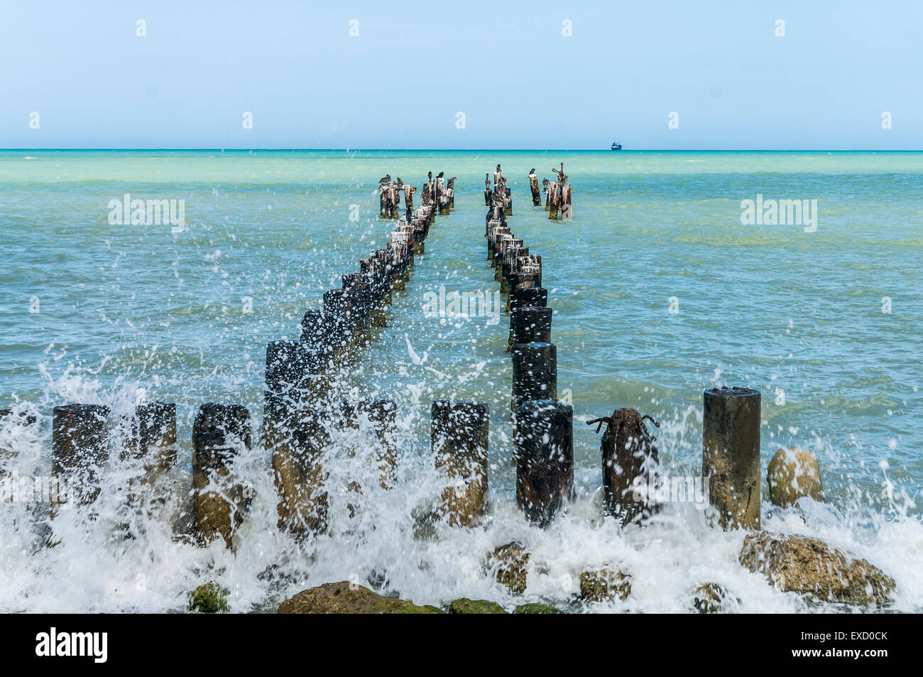 Onde si infrangono attraverso pile sulla spiaggia di Manaure, La Guajira, Colombia. Foto Stock
