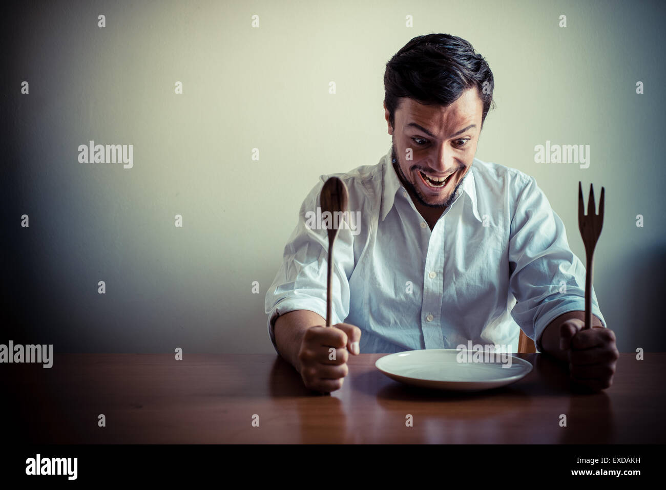 Giovane uomo elegante con camicia bianca di mangiare in pasto alle spalle di una tabella Foto Stock