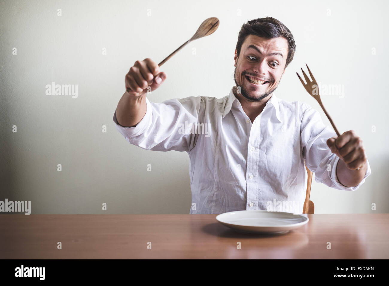 Giovane uomo elegante con camicia bianca di mangiare in pasto alle spalle di una tabella Foto Stock