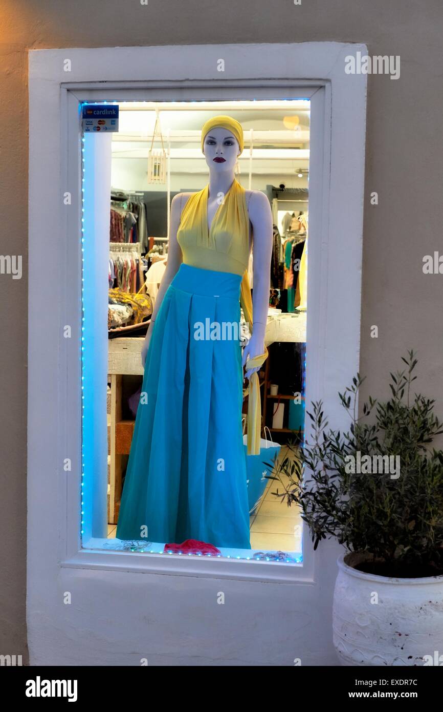 Un manichino nella vetrina di un negozio che indossa un giallo in alto e un mantello blu. Foto Stock
