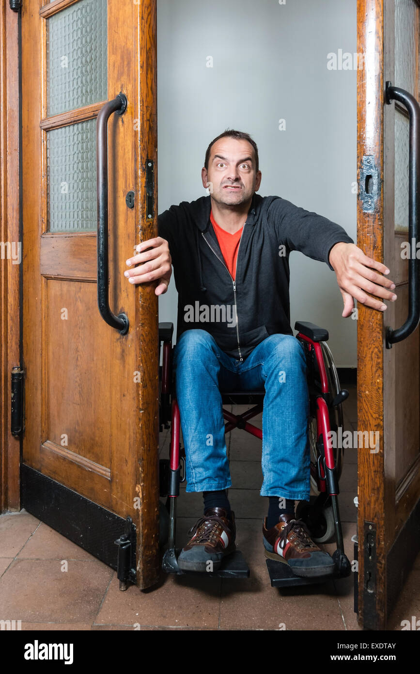 Uomo in sedia a rotelle bloccato tra le porte di oscillazione Foto Stock