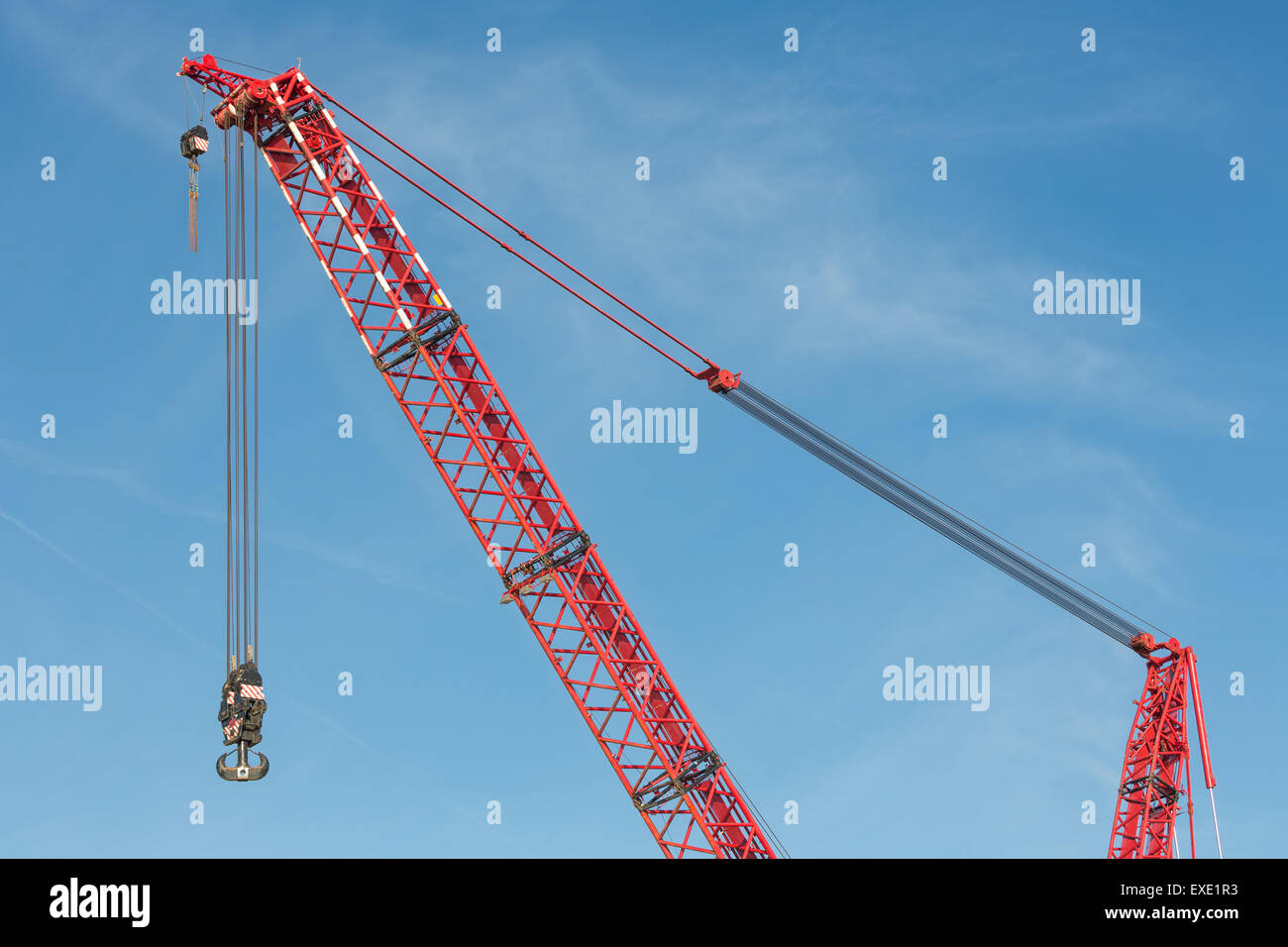 Rosso del braccio della gru con gancio in acciaio contro il cielo blu Foto Stock