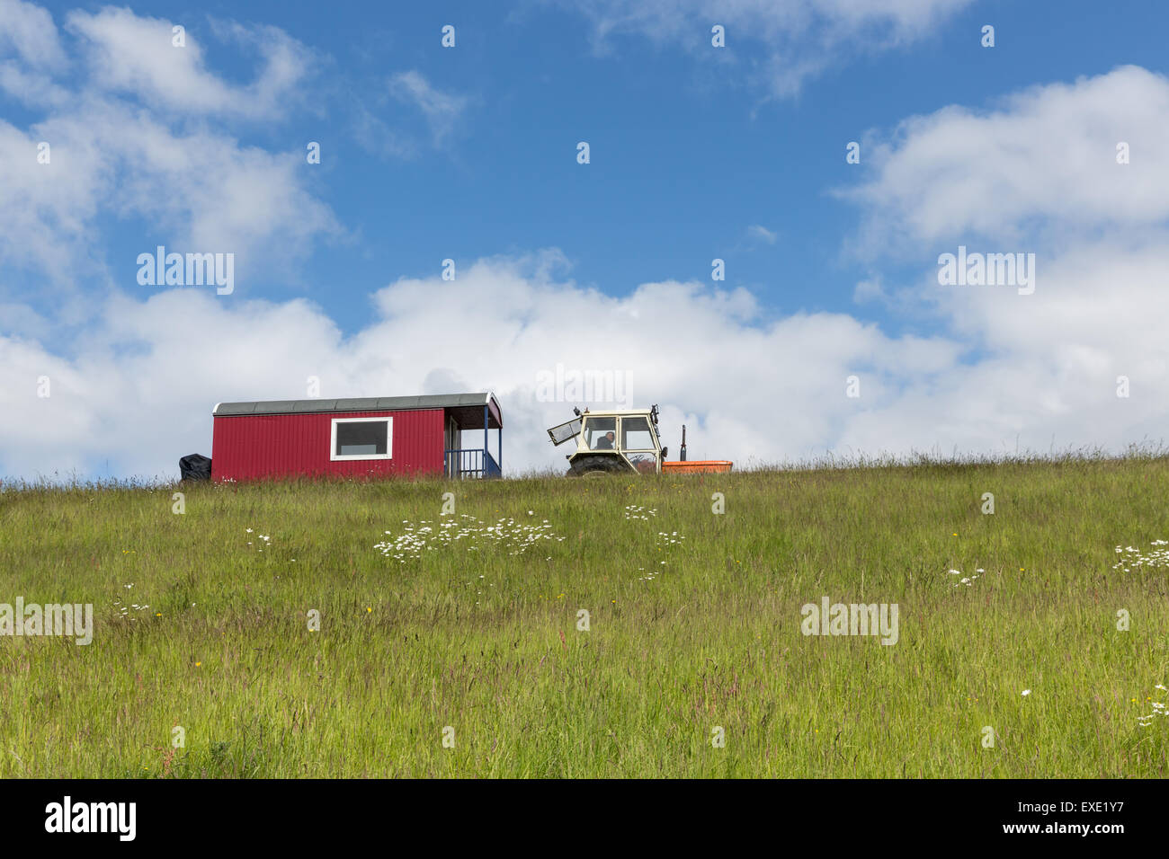 Silhouette di trattore con rimorchio casa su una collina contro un cielo blu Foto Stock