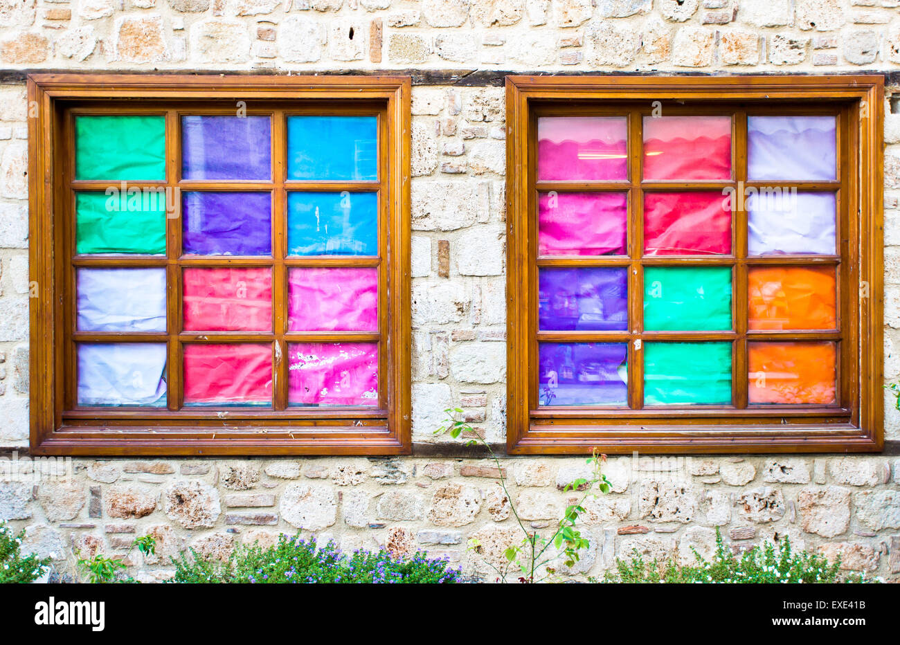 Due finestre in una parete di mattoni coperti da carta colorata Foto Stock