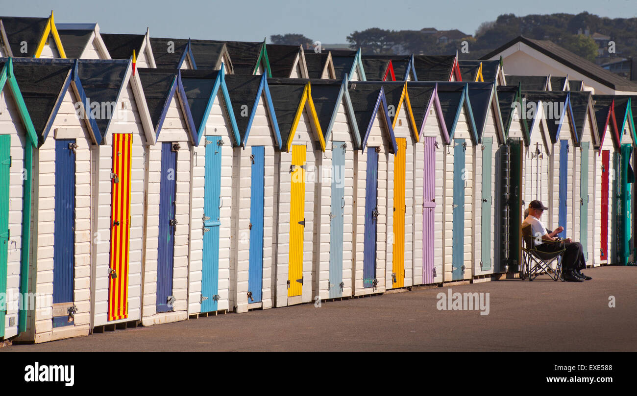 Spiaggia di capanne schierate dal litorale con un singolo sitter in Norfolk, Regno Unito Foto Stock