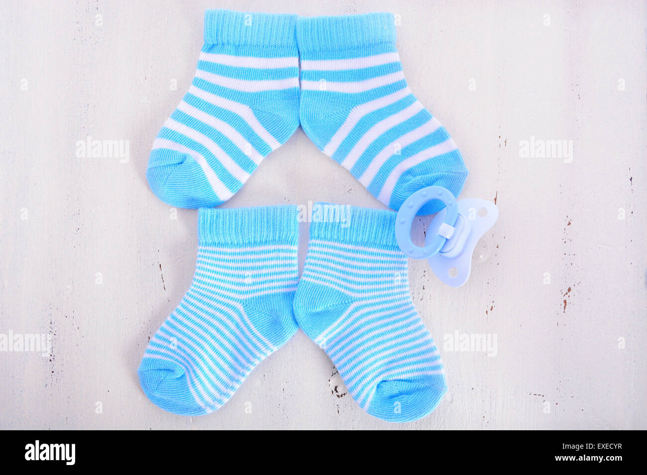Il suo un ragazzo Baby doccia o il concetto di vivaio con calzini e succhiotto ciuccio su bianco shabby chic di legno Foto Stock