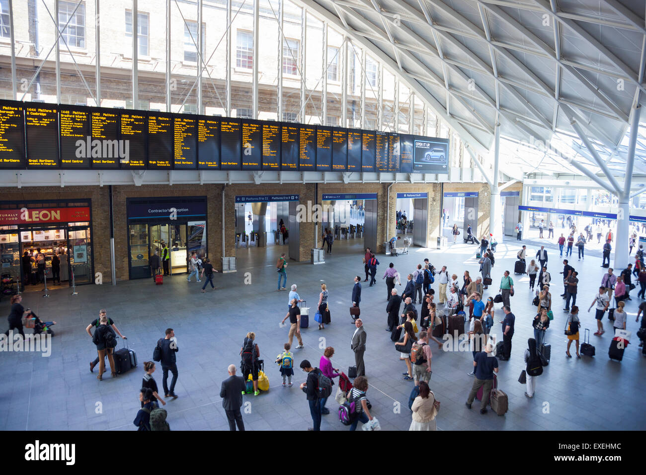 Pendolari guardando le partenze board presso la stazione ferroviaria di King's Cross - Londra, Inghilterra Foto Stock