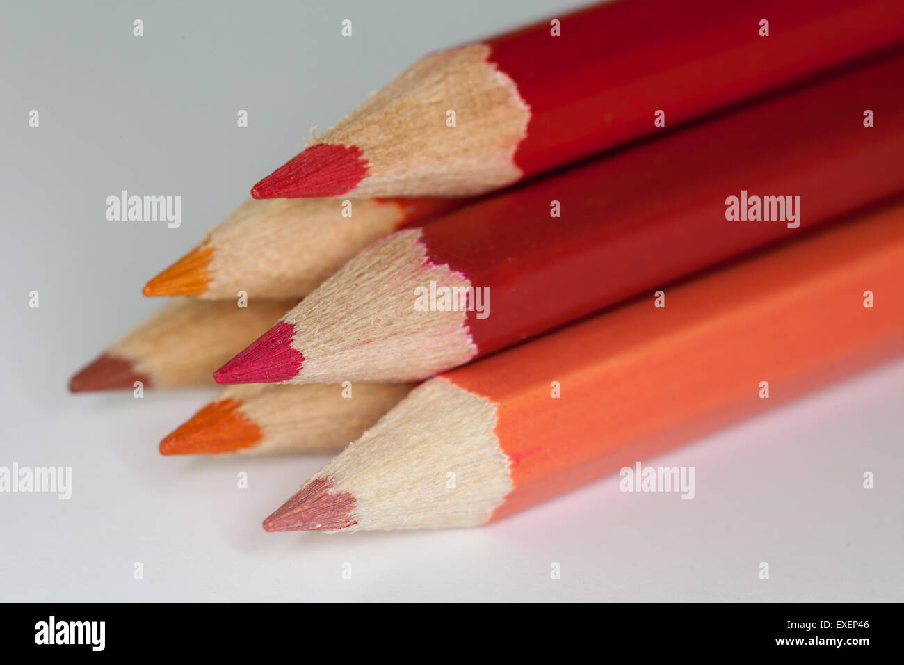Matite impilati visualizzazione di colori caldi contro uno sfondo bianco con focus su sulle punte delle matite. Foto Stock