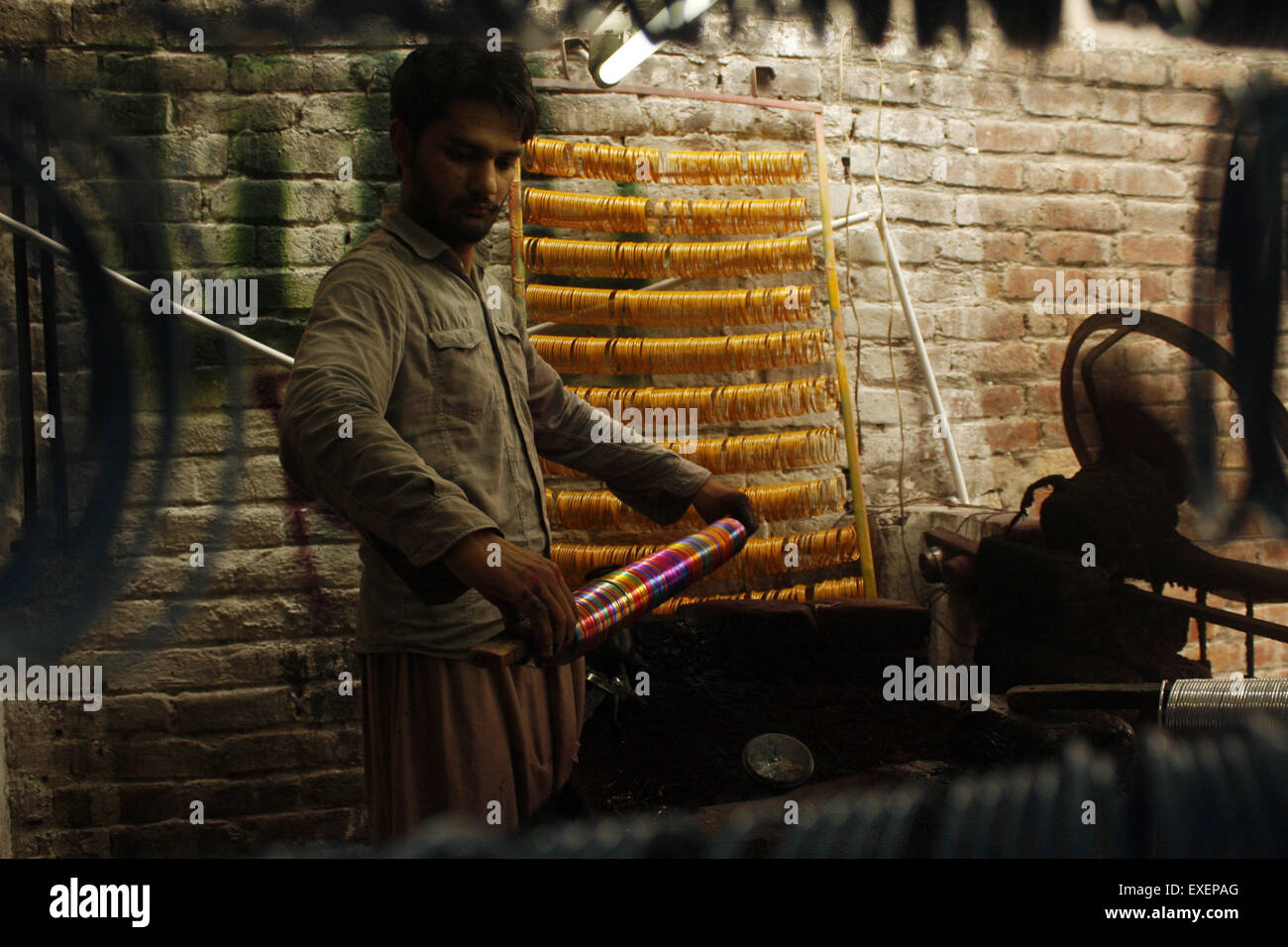 Lahore. 13 Luglio, 2015. Un lavoratore lavora in una fabbrica di bangle precedendo di Eid-al-Fitr festival in Pakistan orientale di Lahore, 13 luglio 2015. Domanda di bangle aumenta prima di Eid vacanze in Pakistan. © Jamil Ahmed/Xinhua/Alamy Live News Foto Stock