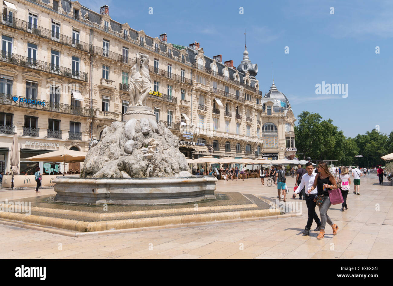 Coppia giovane oltrepassando la statua di tre grazie a Place de la Comédie, Montpellier, Francia, Europa Foto Stock