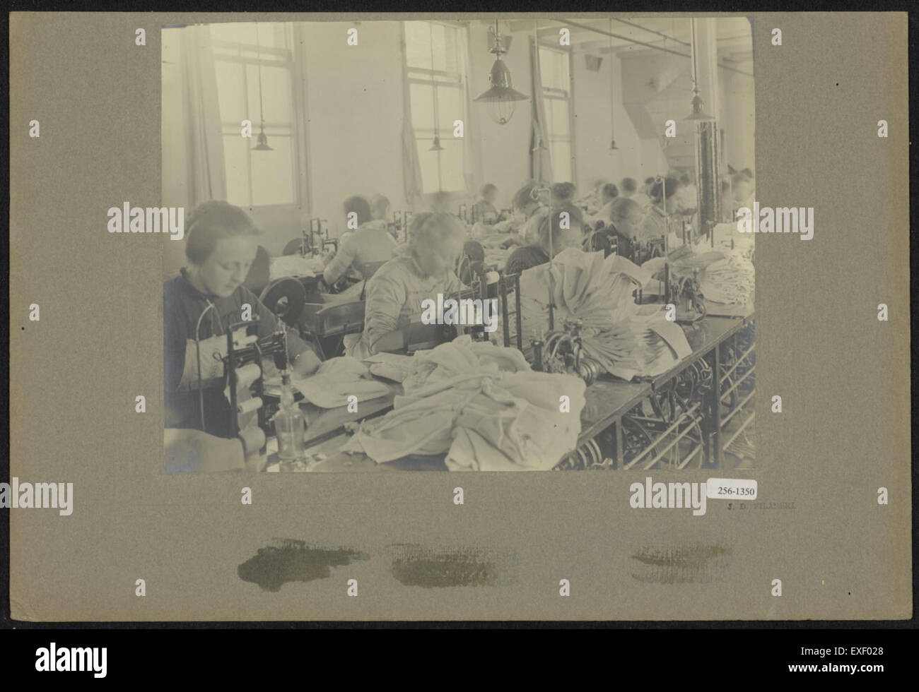 Questa foto storica mostra un laboratorio di cucito, o "naaiatelier", che cattura l'artigianato e l'atmosfera di un laboratorio tessile del passato. Foto Stock