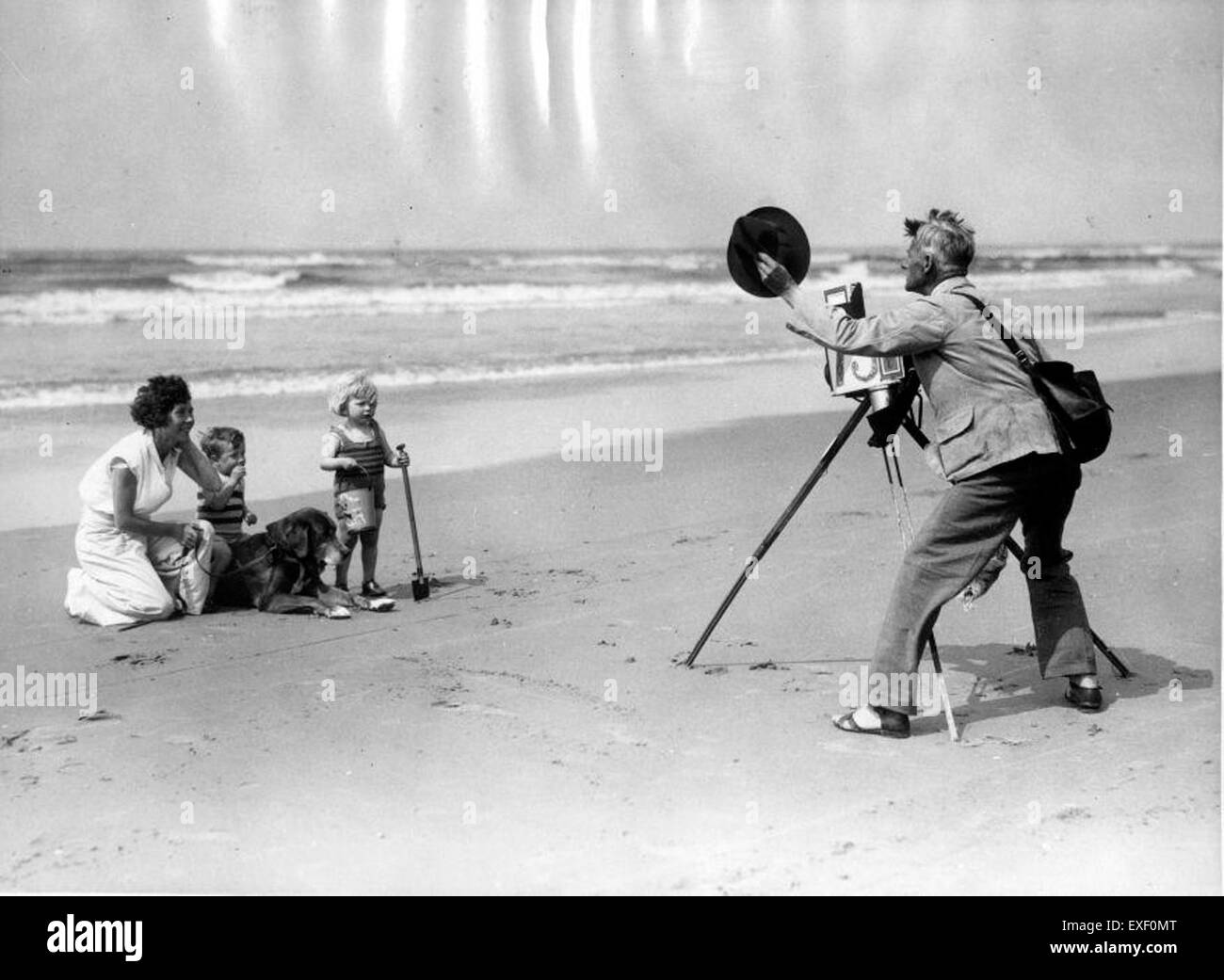Questa immagine mostra il lavoro di un fotografo di spiaggia, catturando le viste panoramiche della costa e le persone sulla spiaggia. Viene evidenziato il ruolo del fotografo nella documentazione della vita in spiaggia, dei paesaggi e delle attività ricreative. Foto Stock