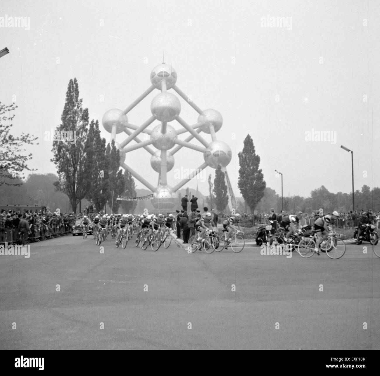 Ciclisti su strada che passano davanti all'Atomium di Bruxelles, un simbolo dell'ottimismo del dopoguerra e dell'architettura modernista della città, costruito per l'Esposizione Universale del 1958. Foto Stock