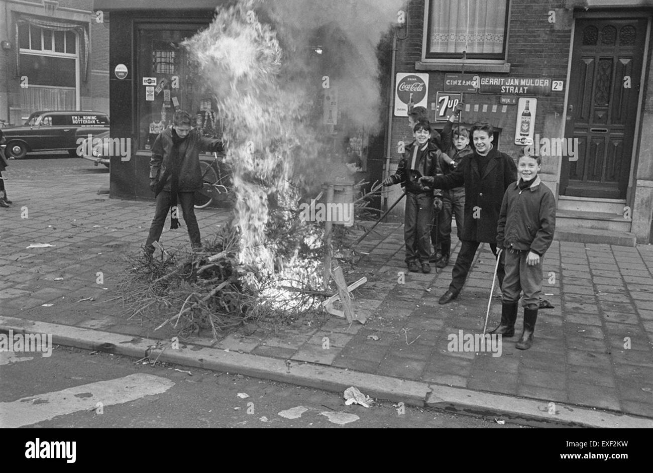 La scena intitolata "Kerstboombrandjes door de jeugd in Rotterdam" raffigura un incendio all'albero di Natale causato dai giovani a Rotterdam. Questa immagine storica ritrae le questioni sociali dell'epoca, evidenziando l'impatto di un comportamento avventato sulla comunità. Foto Stock