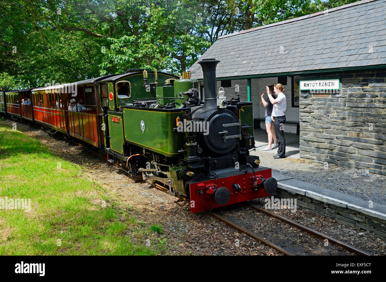 Talyllyn Railway n. 7 "Tom Rolt' passa Rhydyronen station con giovani donne sulla piattaforma sventolano al treno. Foto Stock