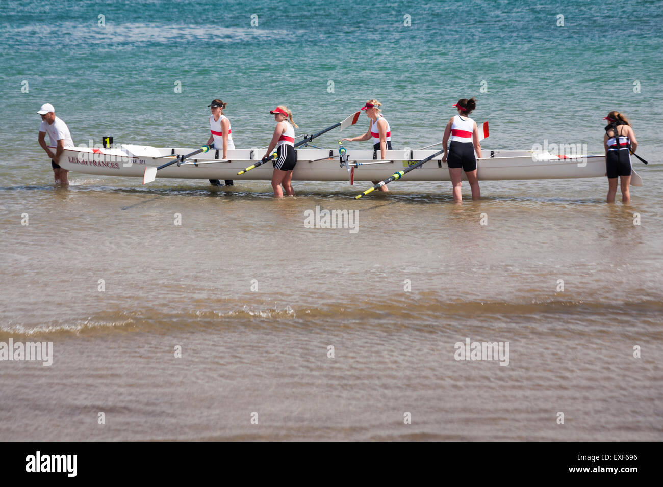 Donne rematori di barca di sollevamento al di fuori del mare a Swanage regata in giugno Foto Stock
