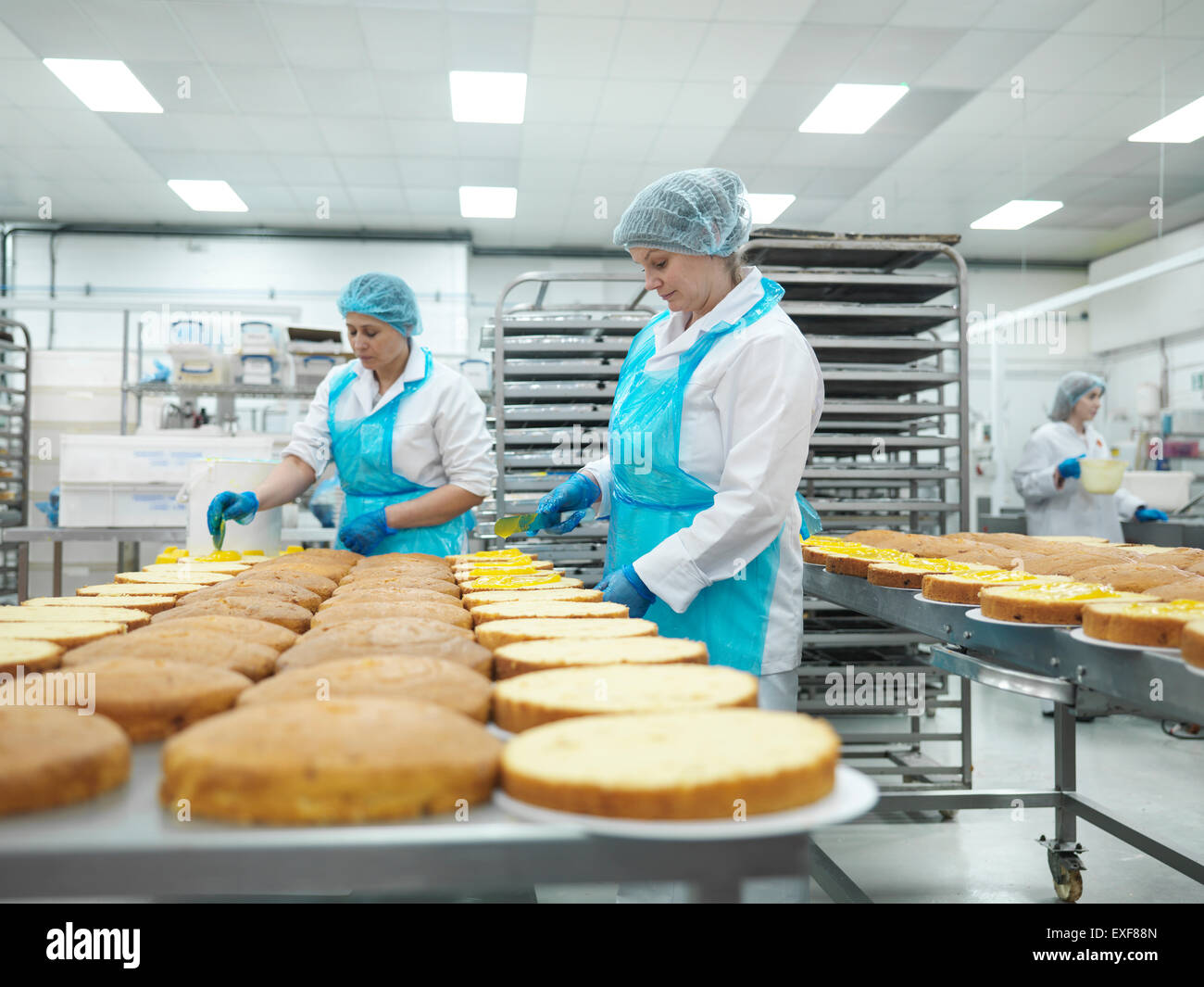 I lavoratori di sesso femminile diffusione di riempimento su torte in fabbrica di torta Foto Stock