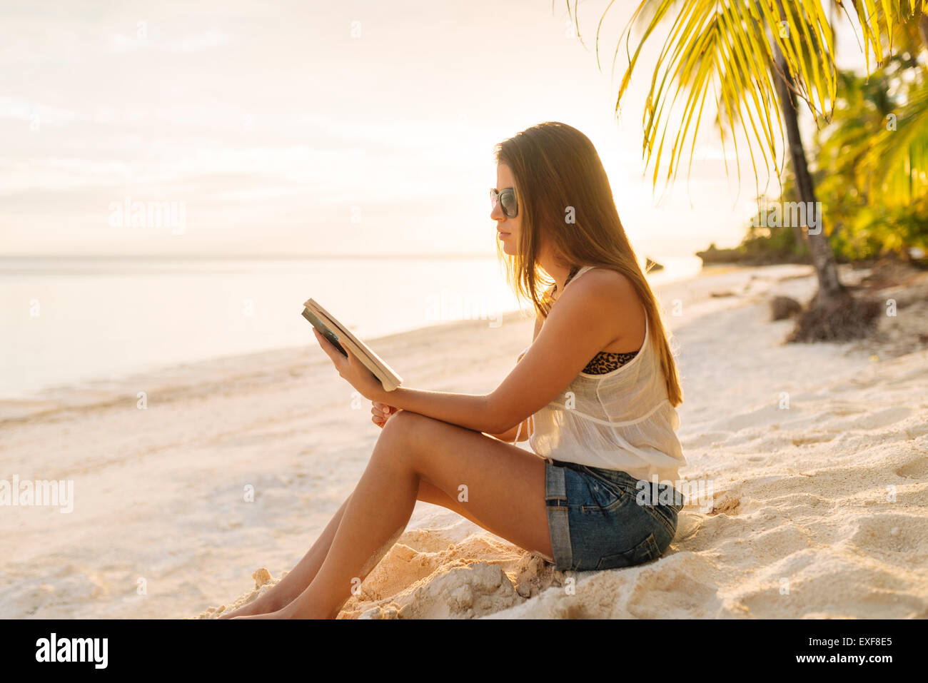 Giovane donna leggendo un libro sul eun beach, Provincia di Bohol, Filippine Foto Stock