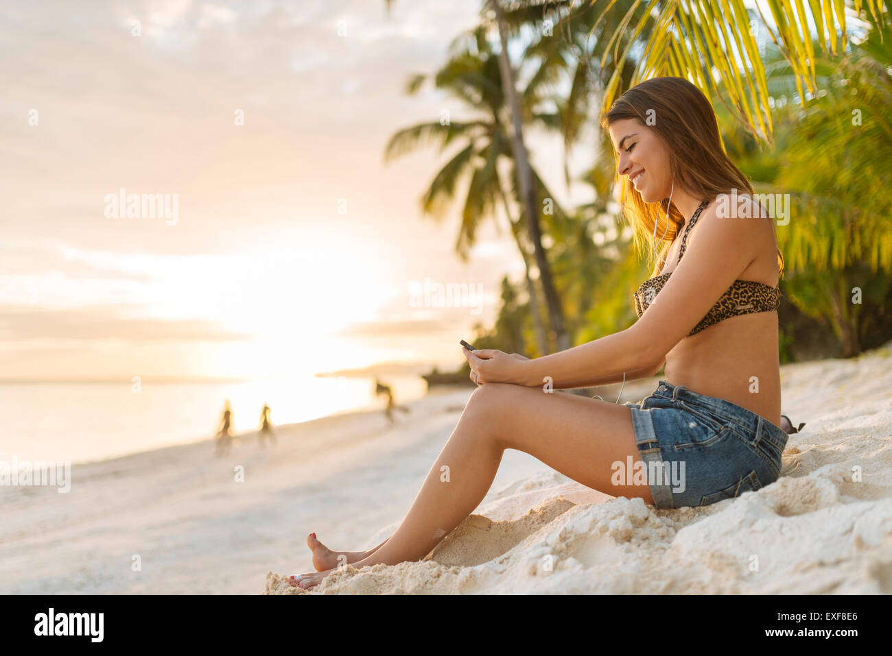 Giovane donna smartphone la lettura di testi su eun beach, Provincia di Bohol, Filippine Foto Stock