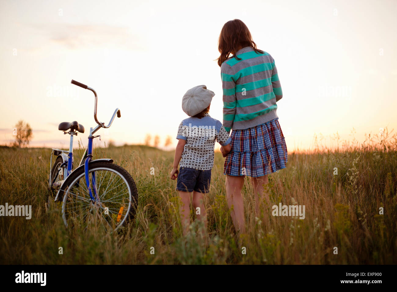 Vista posteriore del ragazzo e madre tenendo le mani nel campo al tramonto, Sarsy villaggio, nella Regione di Sverdlovsk, Russia Foto Stock