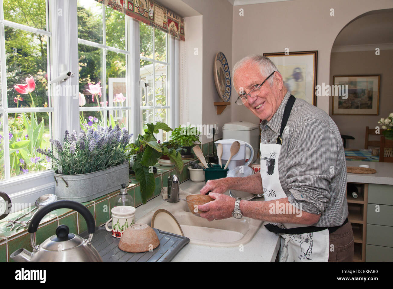 Senior uomo in cucina, lavaggio piatti Foto Stock