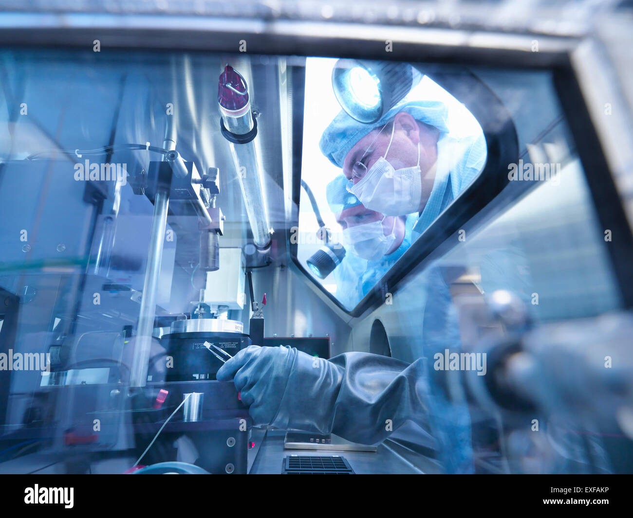 Lavoratori di elettronica esaminando sigillato stazione di lavoro finestra in camera pulita laboratorio Foto Stock
