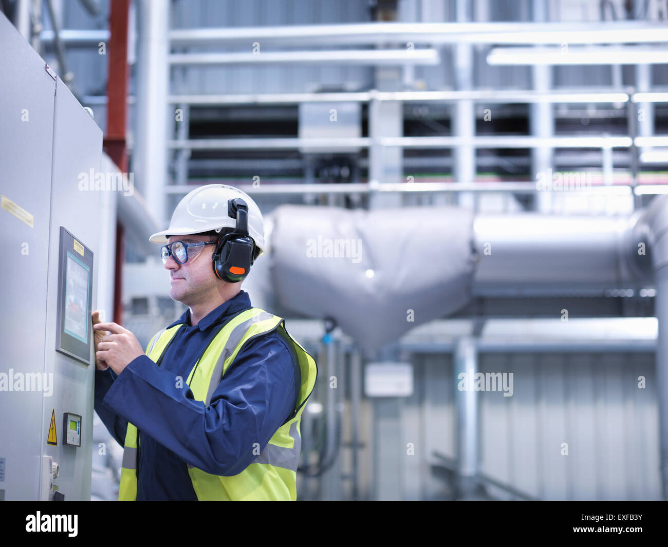 Lavoratore utilizzando controlli del touchscreen nella centrale elettrica a gas Foto Stock