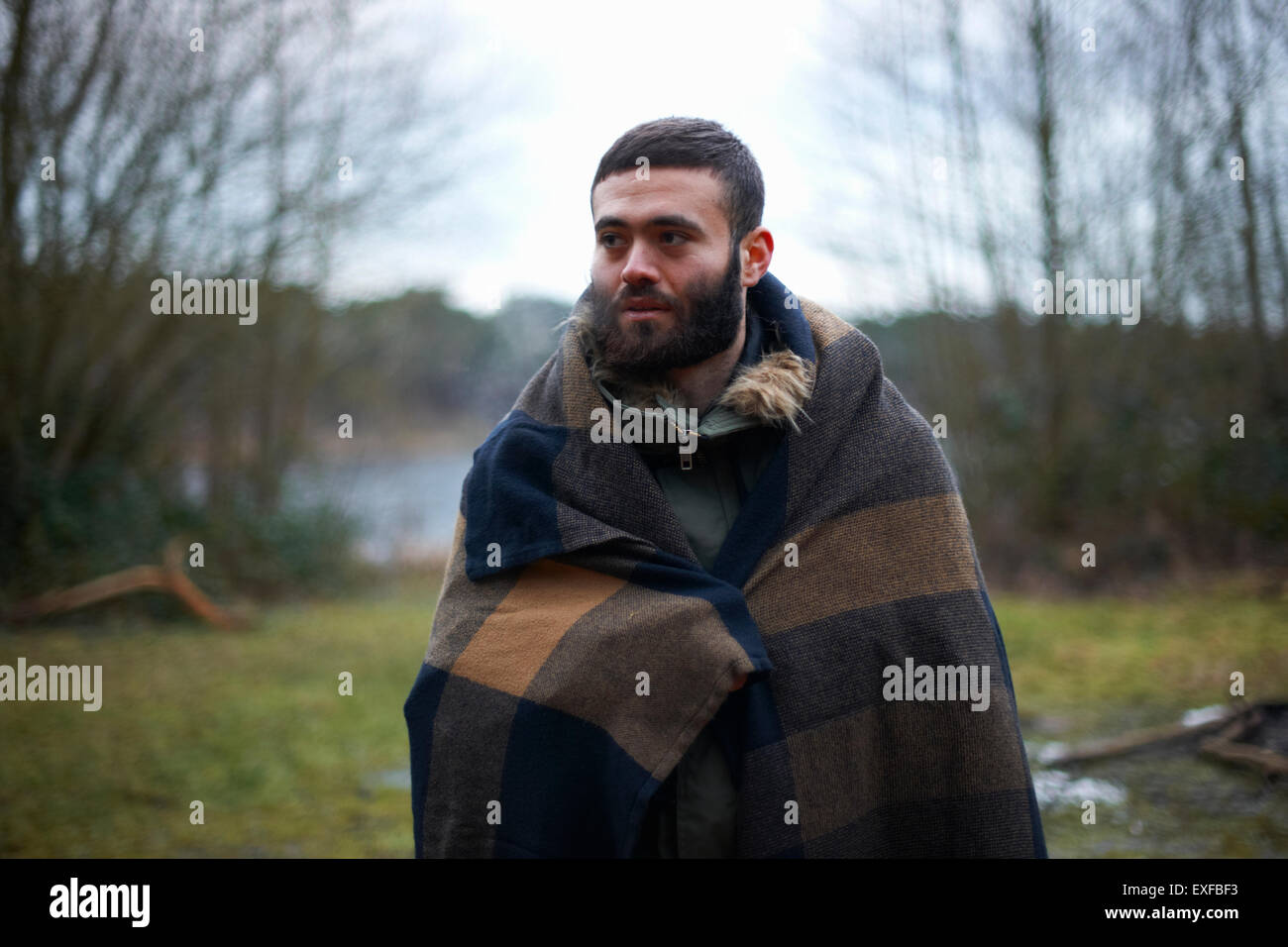 Giovane maschio camper avvolto in una coperta di boschi Foto Stock