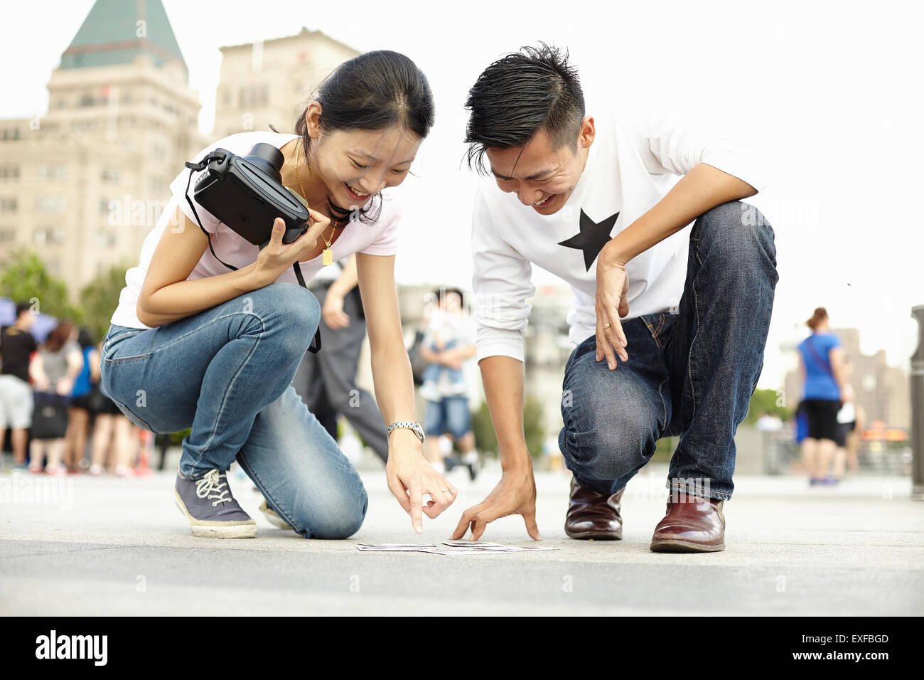 Turista giovane guardando in giù sul marciapiede a pellicola istante fotografie, il Bund, Shanghai, Cina Foto Stock