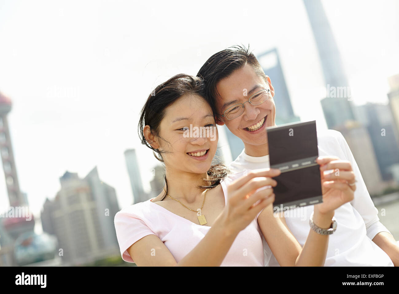 Turista giovane guardando film istantanea fotografie, il Bund, Shanghai, Cina Foto Stock