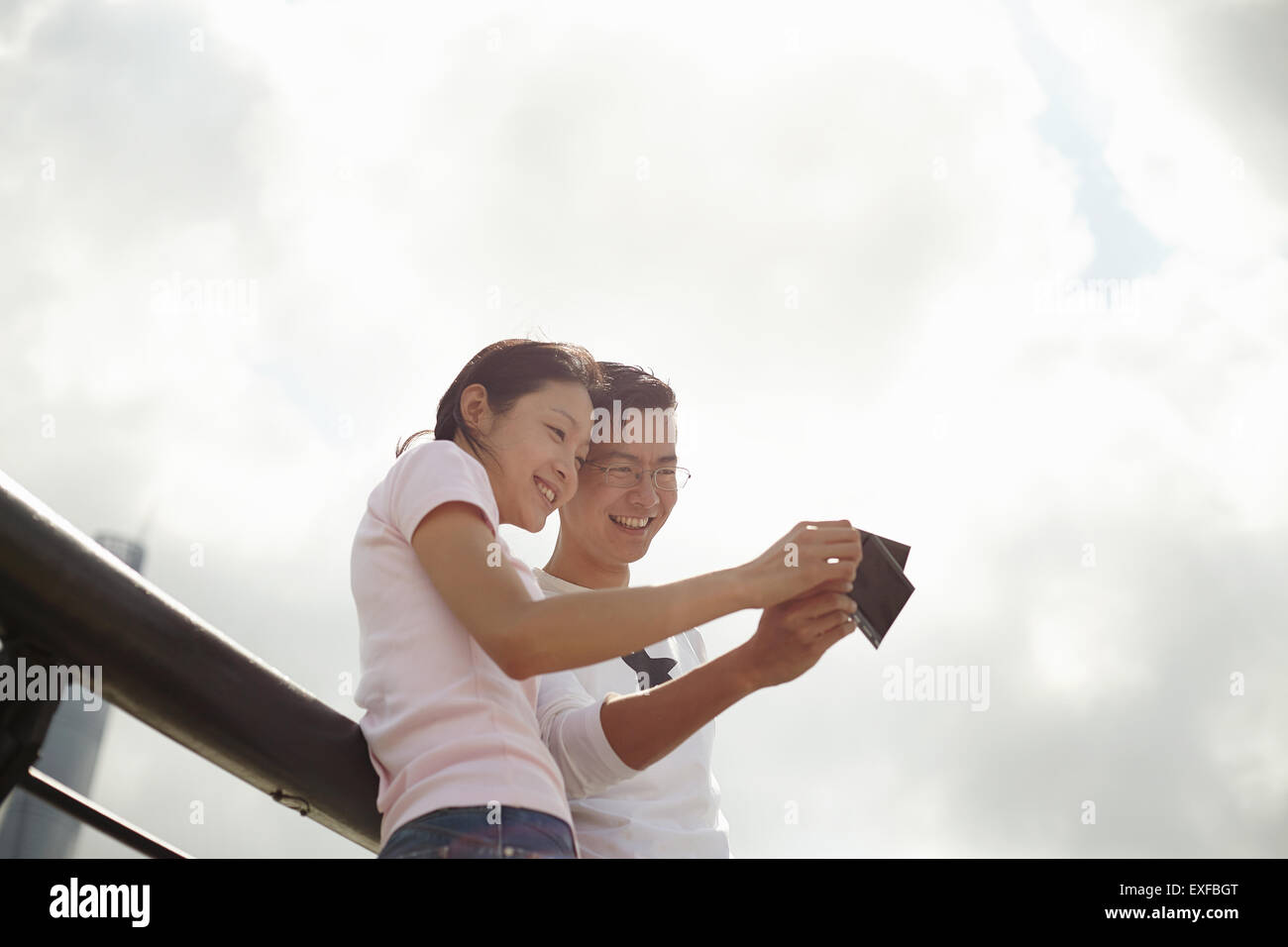 Basso angolo vista del turista giovane guardando film istantanea fotografie, il Bund, Shanghai, Cina Foto Stock