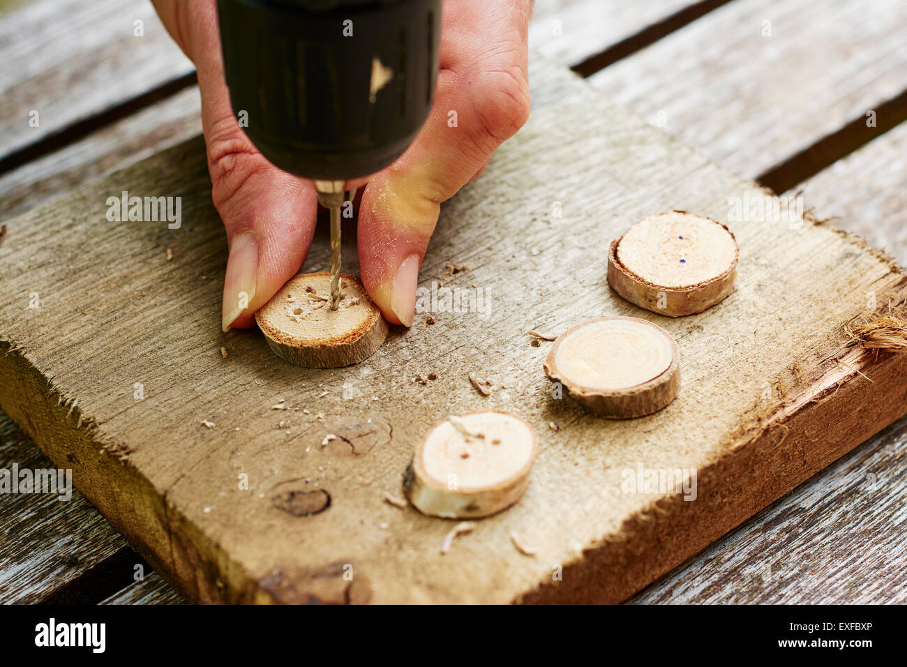 Uomo di trapanare i fori nei pulsanti di legno. Foto Stock