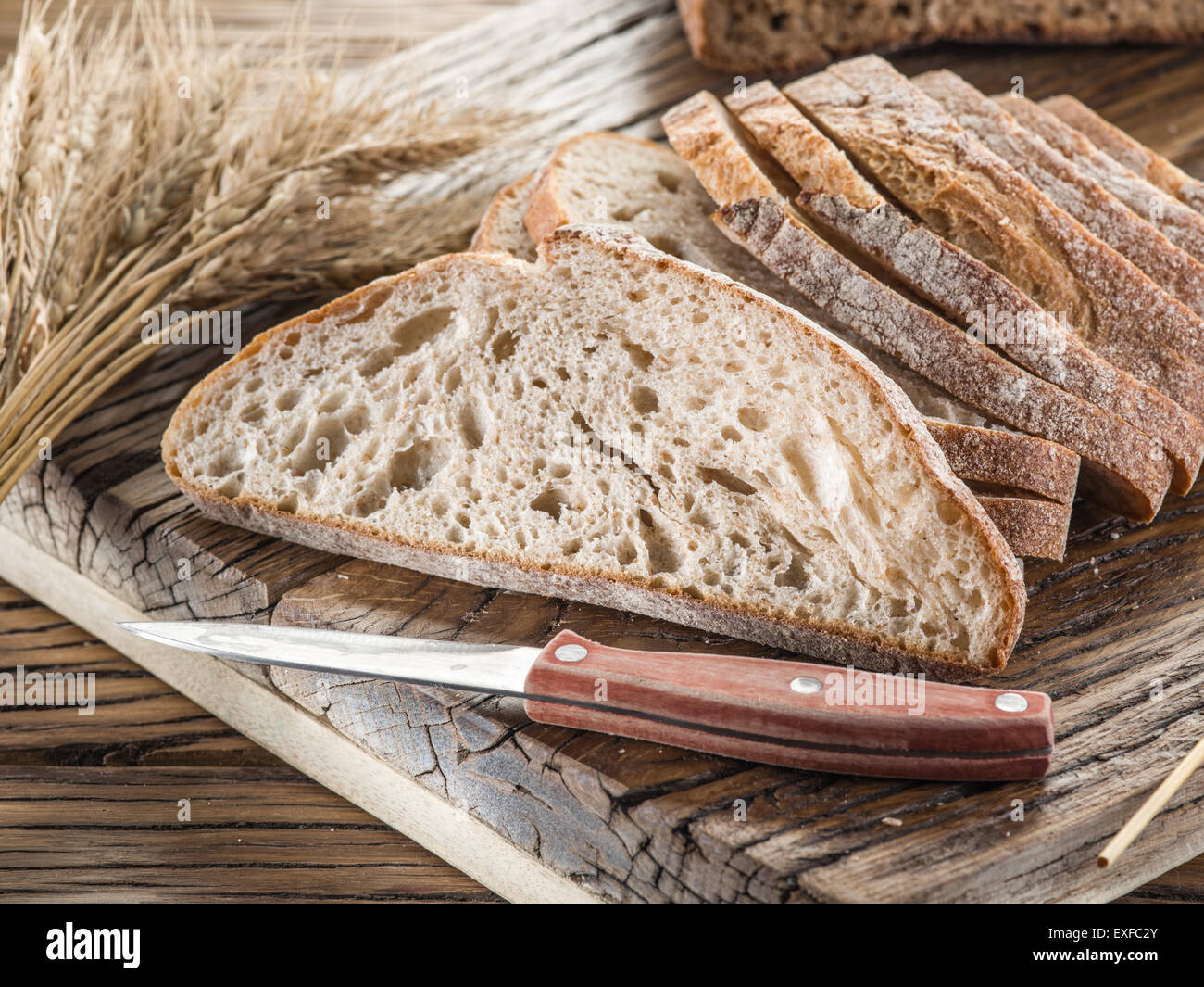 Fette di pane nero sul vecchio asse di legno. Foto Stock