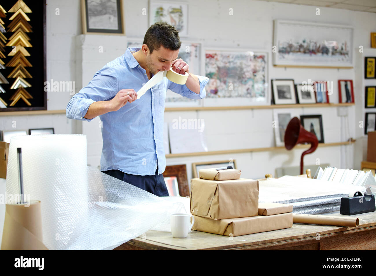 L'uomo bolla telaio incarto sul tavolo in picture corniciai workshop Foto Stock