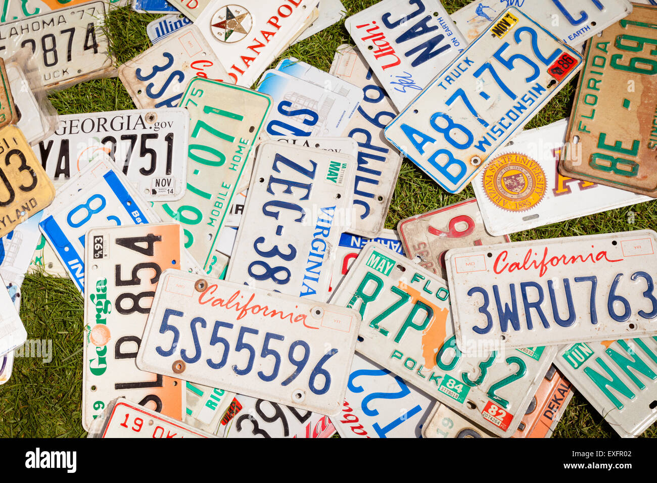 Casuale di una pila di sparse targhe di immatricolazione di automobili americane, sull'erba. Foto Stock