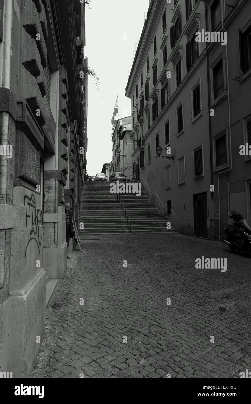 Bianco e nero street photography immagine di una strada laterale a Roma e in alcune fasi con un uomo di guardare direttamente la fotocamera Foto Stock