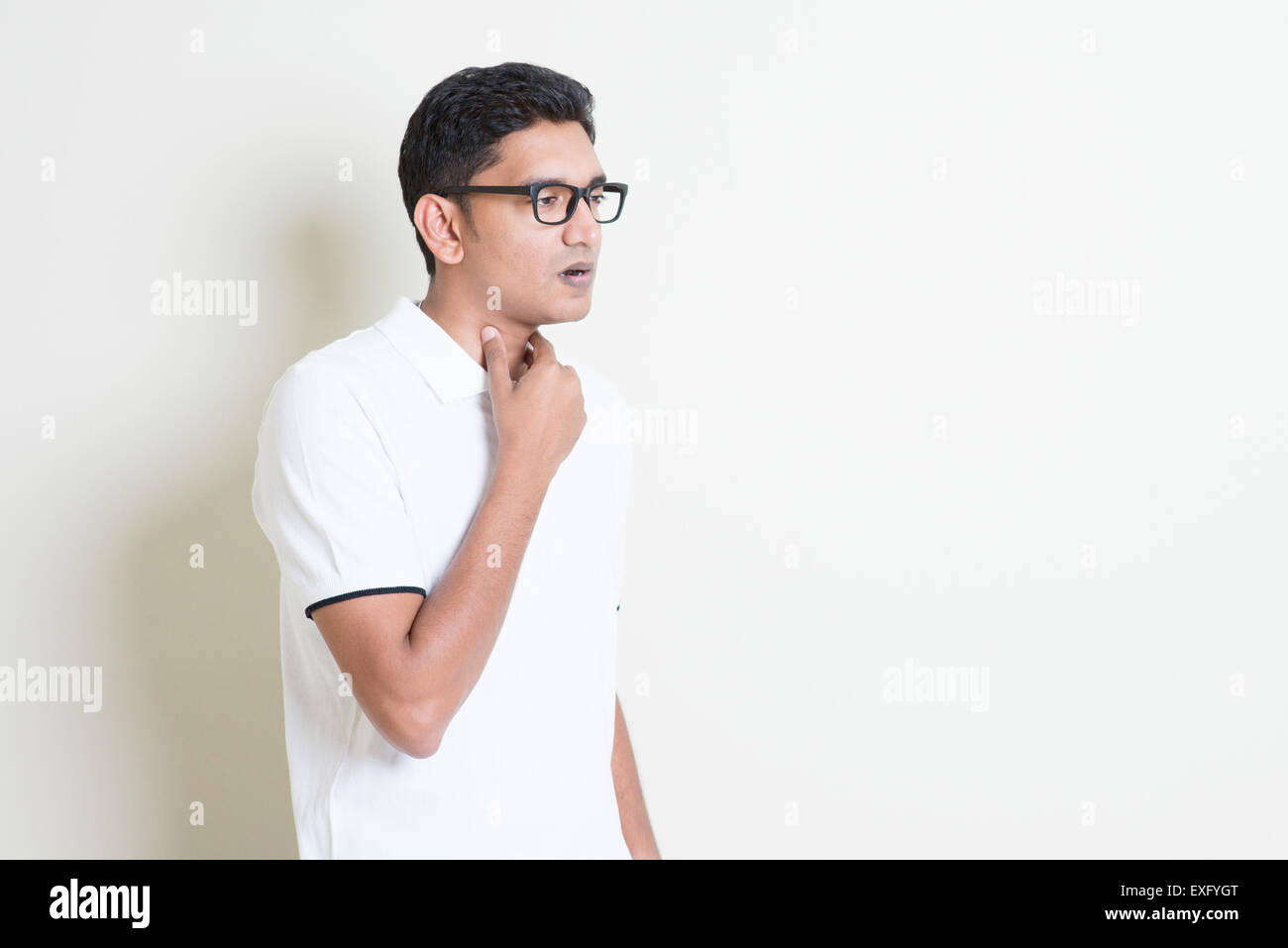 Ritratto di ragazzo indiano mal di gola, la mano sul collo della gola di compensazione. Uomo asiatico in piedi su sfondo semplice con ombra e copiare sp Foto Stock